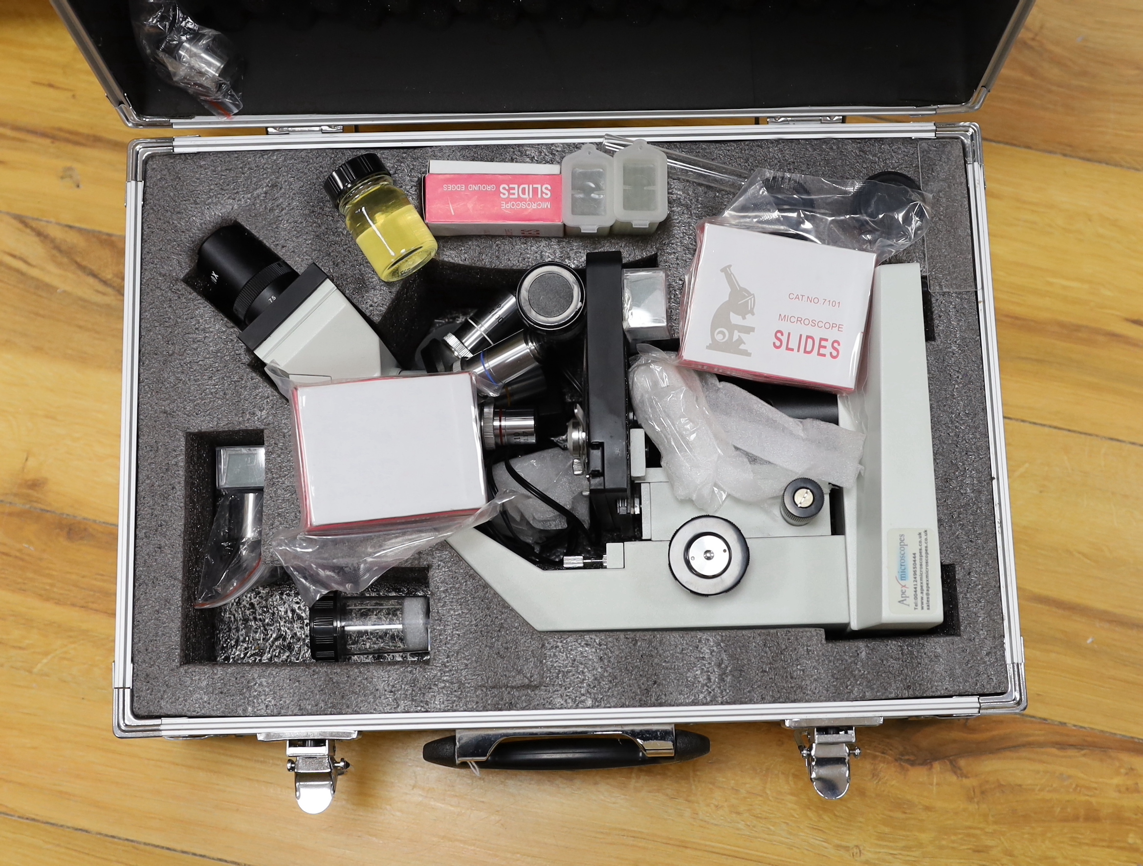 A cased binocular Apex Researcher Compound Microscope with a selection of accessories, slides, Apex ‘Minigrab’, handbook; ’Adventures with a Microscope’ by Richard Headstrom, etc., microscope 34cm high